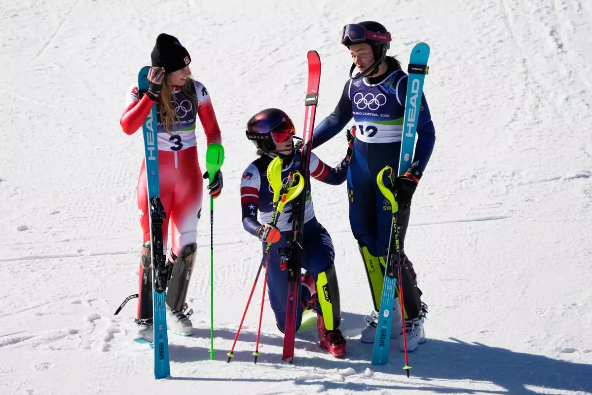 United States' Mikaela Shiffrin, center, winner of an alpine ski, women's slalom race, celebrates with second-placed Switzerland's Camille Rast, left, and third-placed Sweden's Anna Swenn Larsson, at the 2026 Winter Olympics, in Cortina d'Ampezzo, Italy, Wednesday, Feb. 18, 2026. (AP Photo/Andy Wong)