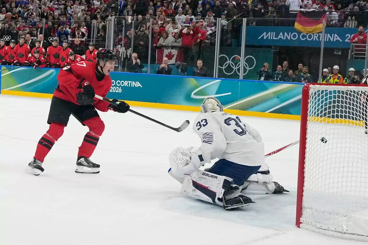 Canada's Macklin Celebrini (17) scores a goal on a penalty shot in the second period against France's goalkeeper Julian Junca (33) during a preliminary round game of men's ice hockey between Canada and France at the 2026 Winter Olympics, in Milan, Italy, Sunday, Feb. 15, 2026. (AP Photo/Hassan Ammar)