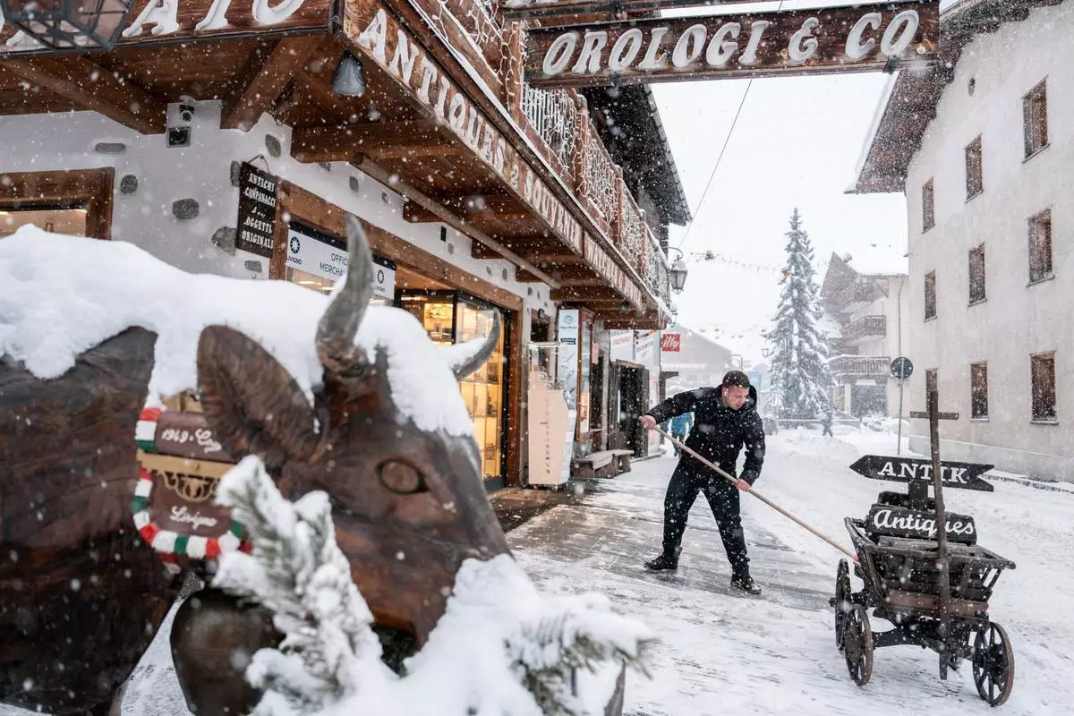 A person removes snow from a storefront during the 2026 Winter Olympics, Thursday, Feb. 19, 2026, in Livigno, Italy. (AP Photo/Julia Demaree Nikhinson)