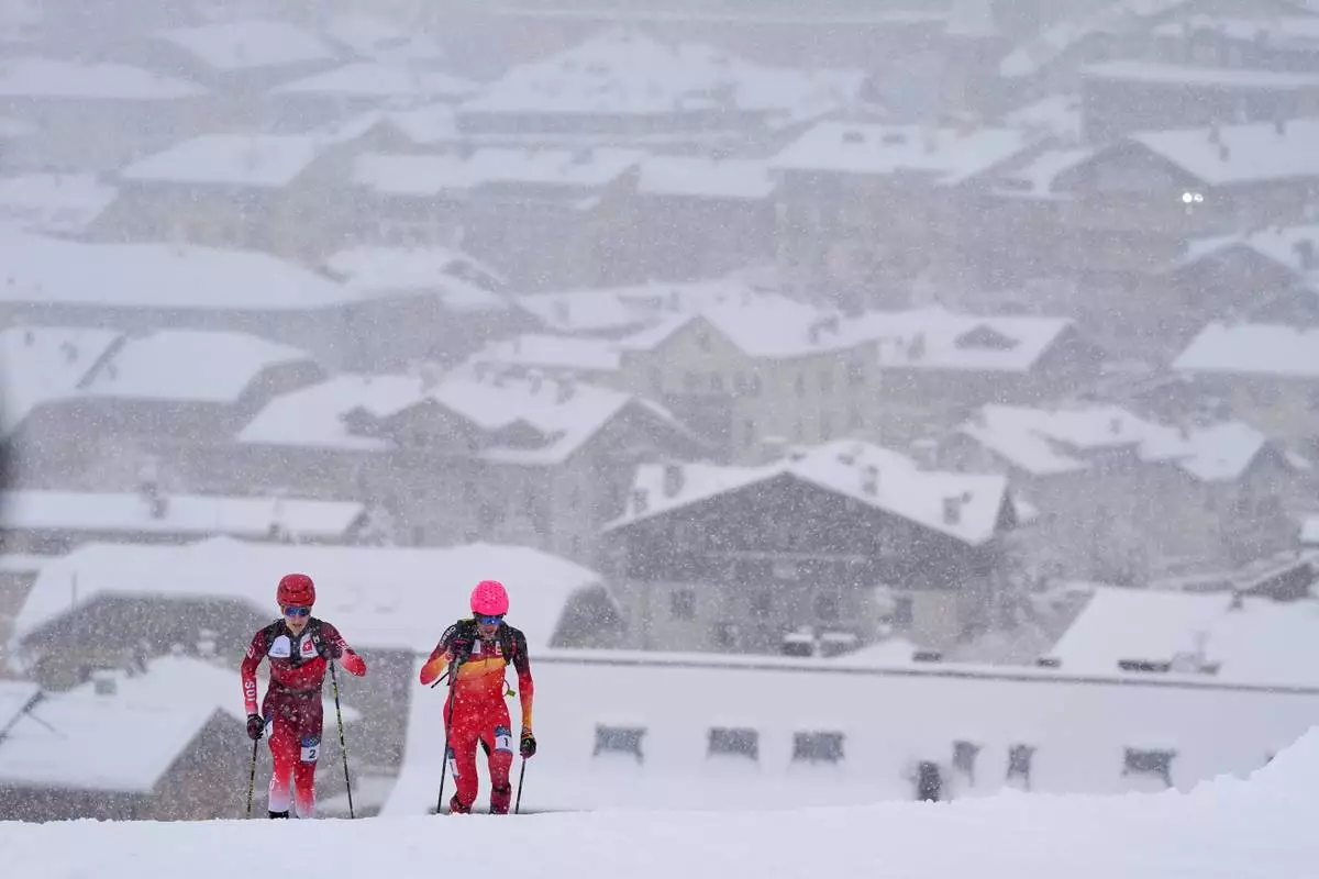 Spain's Oriol Cardona Coll, right, competes alongside Switzerland's Jon Kistler backdropped by a snow covered Bormio village, during a ski mountaineering men's sprint semifinal, at the 2026 Winter Olympics, in Bormio, Italy, Thursday, Feb. 19, 2026. (AP Photo/Rebecca Blackwell)
