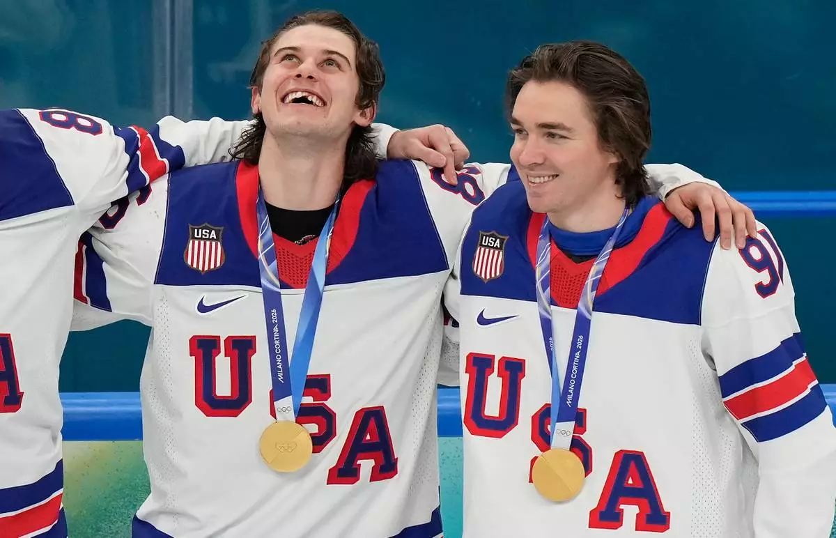 United States' Jack Hughes (86) and Clayton Keller (91) react after receiving their gold medals after the USA defeated Canada in the men's ice hockey gold medal game at the 2026 Winter Olympics, in Milan, Italy, Sunday, Feb. 22, 2026. (AP Photo/Luca Bruno)