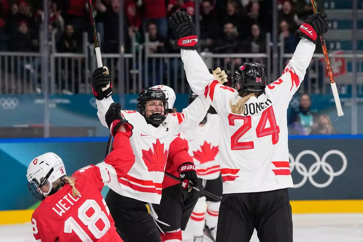 Canada's Natalie Spooner, right, celebrates with Canada's Marie-Philip Poulin after scoring her sides first goal during a preliminary round match of women's ice hockey between Switzerland and Canada at the 2026 Winter Olympics, in Milan, Italy, Saturday, Feb. 7, 2026. (AP Photo/Petr David Josek)