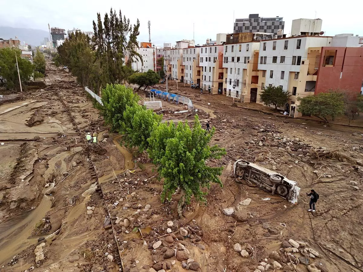A man takes photos on a destroyed road after heavy rain triggered flooding in Arequipa, Peru, Monday, Feb. 23, 2026. (AP Photo/Jose Sotomayor)