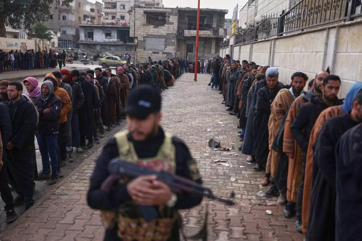 FILE - Former Syrian Democratic Forces members line up at a government-run reconciliation center to obtain official clearance documents stating they have left the group, a move aimed at avoiding further legal prosecution, in Raqqa, northeastern Syria, Feb. 1, 2026. (AP Photo/Ghaith Alsayed, File)