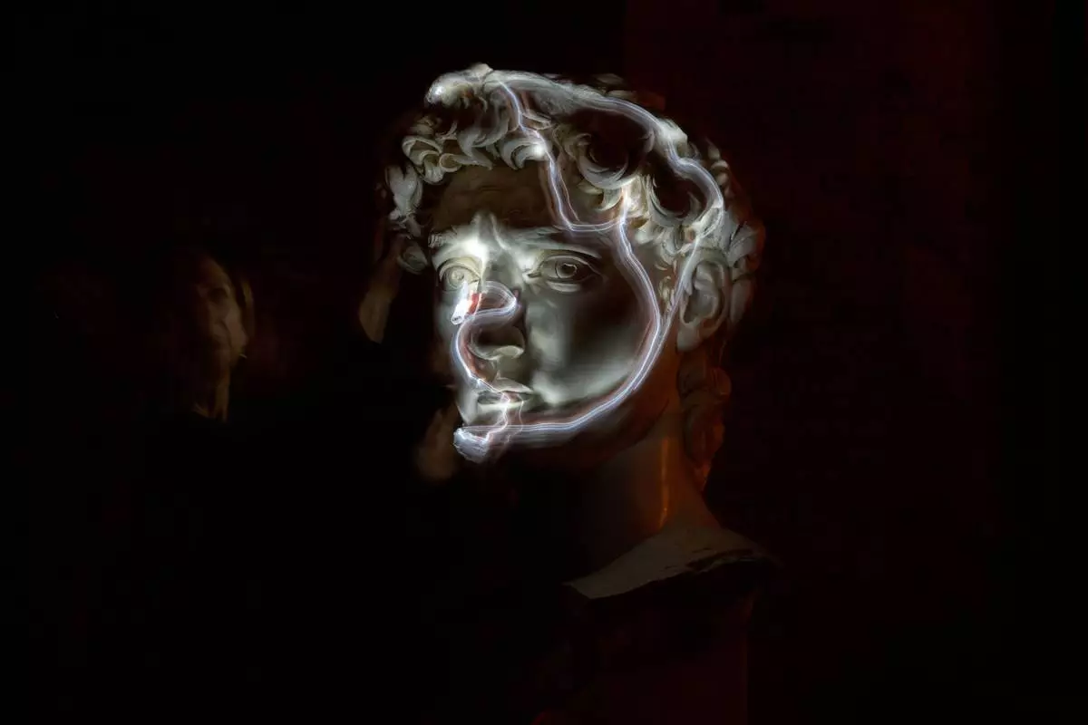 FILE - Stefania Terre, who is blind, uses a small light on her fingers while touching a life-size reproduction of the head of Michelangelo's David as she poses for a long-exposure photograph at the Omero Tactile Museum in Ancona, Italy, Jan. 15, 2026. (AP Photo/Alessandra Tarantino, File)