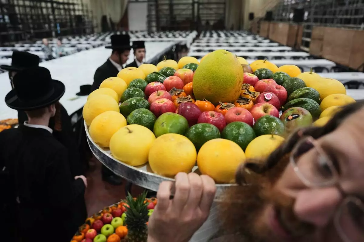 FILE - Ultra-Orthodox Jews from the Sanz Hasidic dynasty prepare a table with fruit to celebrate the Jewish holiday of Tu Bishvat, or the "New Year of the Trees," in Netanya, Israel, Feb. 2, 2026. (AP Photo/Ariel Schalit, File)
