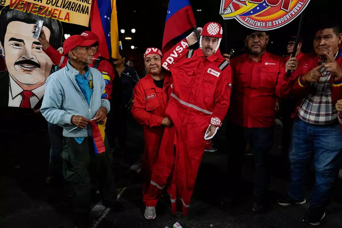 FILE - A PDVSA worker of the state-owned oil company carries a cutout of former President Nicolas Maduro dressed as an oil worker during a rally to back an oil reform bill proposed by acting President Delcy Rodriguez to loosen state control and open the industry to private and foreign investment in Caracas, Venezuela, Jan. 29, 2026. (AP Photo/Ariana Cubillos, File)