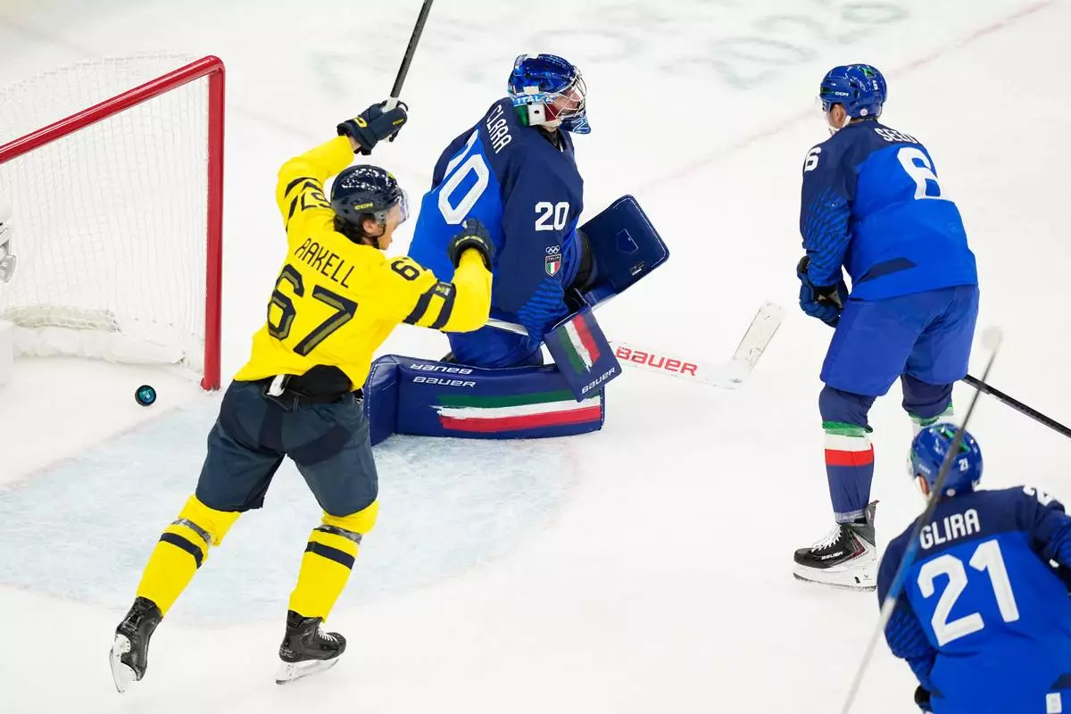 Sweden's Rickard Rakell, left, celebrates a goal scored past Italy's goalkeeper Damian Clara, center, during a preliminary round match of men's ice hockey between Italy and Sweden at the 2026 Winter Olympics, in Milan, Italy, Wednesday, Feb. 11, 2026. (AP Photo/Hassan Ammar)