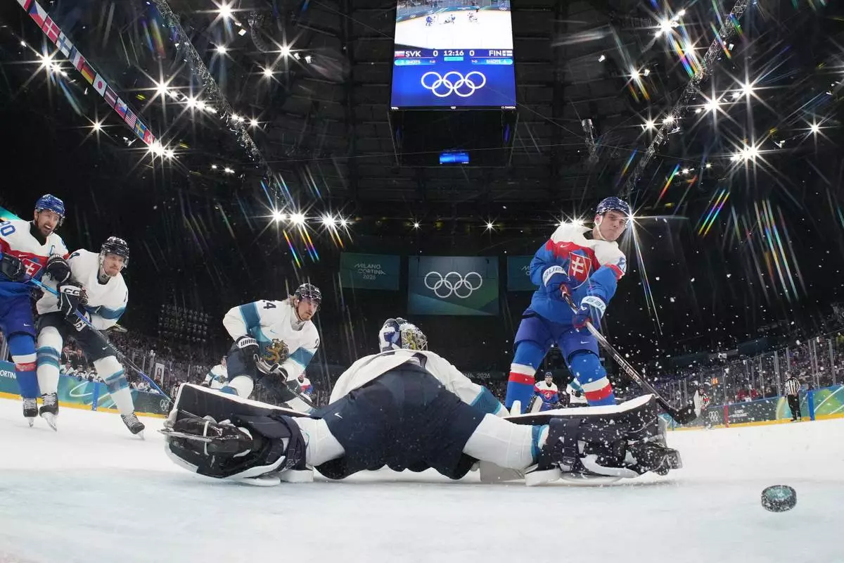 Slovakia's Juraj Slafkovsky (20) scores a goal against Finland's goalkeeper Juuse Saros (74) in the first period during a preliminary round match of men's ice hockey between at the 2026 Winter Olympics, in Milan, Italy, Wednesday, Feb. 11, 2026. (Mike Segar/Pool Photo via AP)