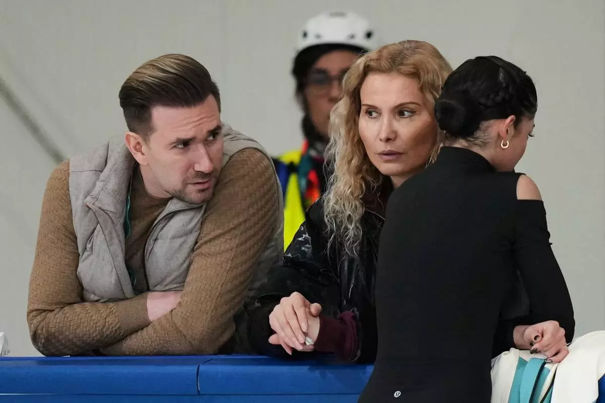 Individual Neutral Athlete Adeliia Petrosian, right, speaks with coach Eteri Tutberidze, center, and choreographer Daniil Gleikhengauz, during a figure skating practice session at the 2026 Winter Olympics, in Milan, Italy, Monday, Feb. 16, 2026. (AP Photo/Stephanie Scarbrough)