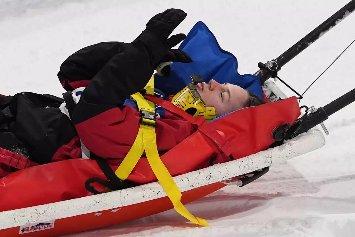 Canada's Cassie Sharpe blows kisses as medics stretcher her off after crashing during the women's freestyle skiing halfpipe qualifications at the 2026 Winter Olympics, in Livigno, Italy, Thursday, Feb. 19, 2026. (AP Photo/Gregory Bull)
