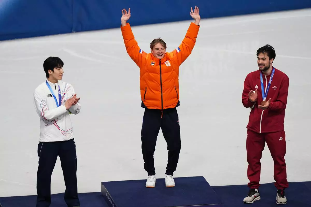 Gold medalist Jens van 't Wout of the Netherlands jumps on the podium to receive his medal after the short track speed skating men's 1500m at the 2026 Winter Olympics, in Milan, Italy, Saturday, Feb. 14, 2026. (AP Photo/Francisco Seco)