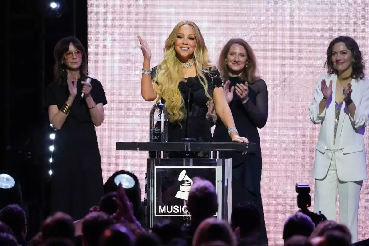 Mariah Carey, center, accepts the 2026 MusiCares Persons of the Year award during MusiCares Person of the Year honoring Mariah Carey on Friday, Jan. 30, 2026, in Los Angeles. (AP Photo/Chris Pizzello)