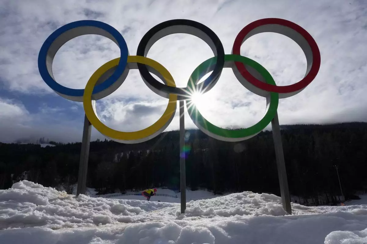 An athlete skis past Olympic rings during a cross country training session at the 2026 Winter Olympics, in Tesero, Italy, Thursday, Feb. 5, 2026. (AP Photo/Kirsty Wigglesworth)