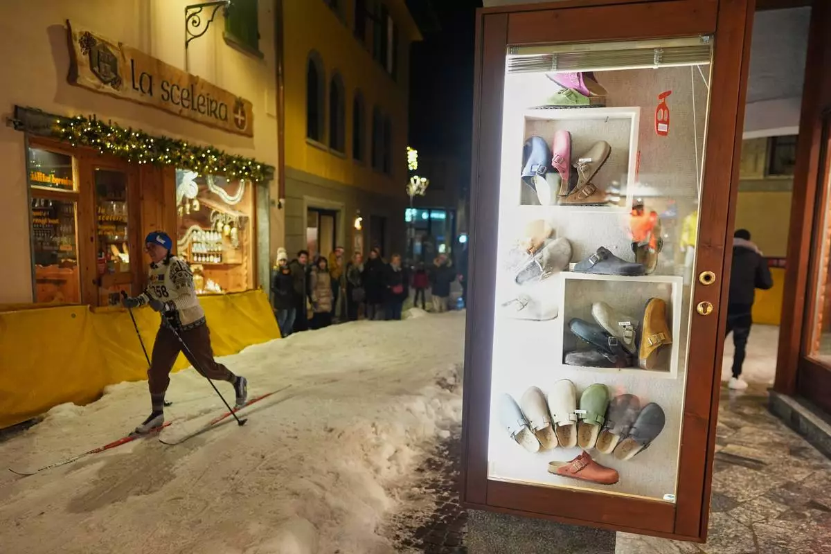 A participant skis past storefronts as Bormio residents compete in an annual cross-country ski race through the streets of the old town, this year coinciding with the 2026 Winter Olympics, in Bormio, Italy, Friday, Feb. 13, 2026. (AP Photo/Rebecca Blackwell)