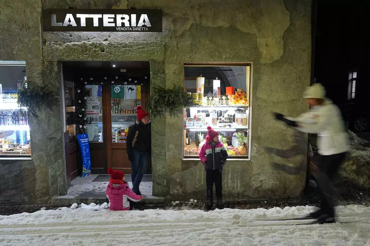 Spectators watch as Bormio residents compete in an annual cross-country ski race through the streets of the old town, this year coinciding with the 2026 Winter Olympics, in Bormio, Italy, Friday, Feb. 13, 2026. (AP Photo/Rebecca Blackwell)