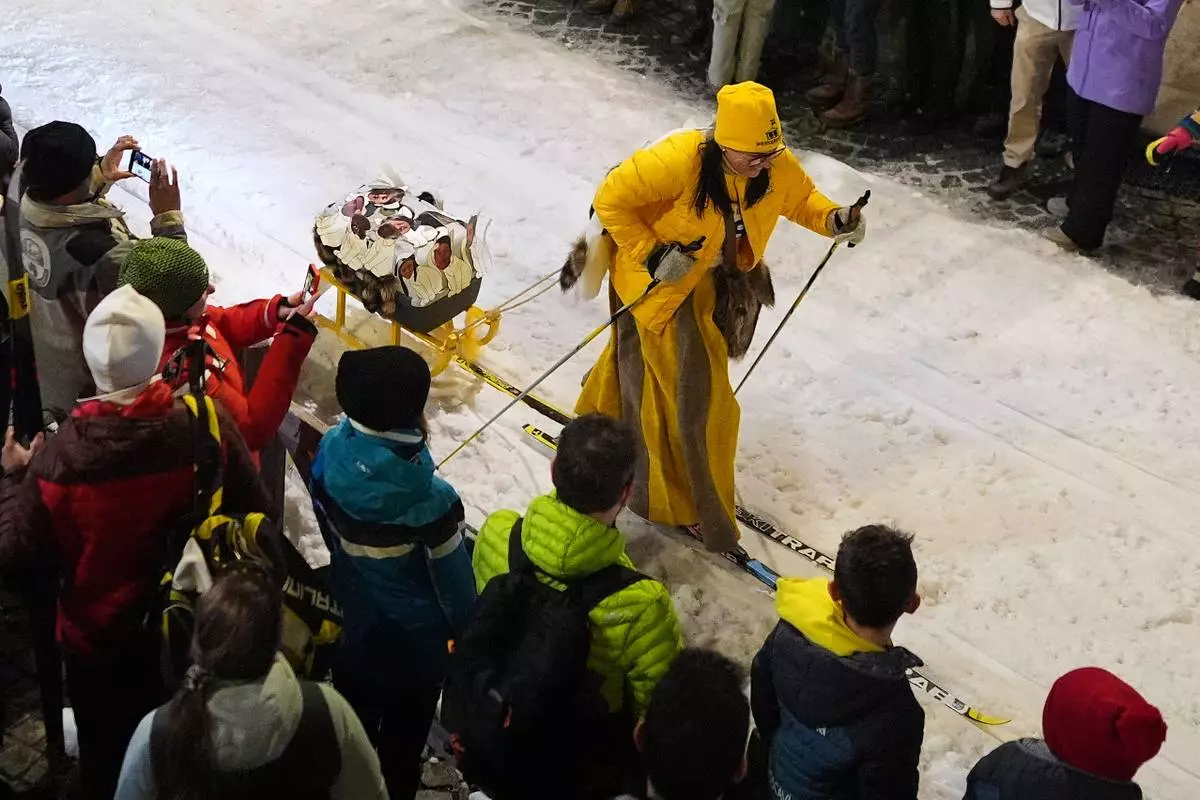 A participant tows a decorated sled as Bormio residents compete in an annual cross-country ski race through the streets of the old town, this year coinciding with the 2026 Winter Olympics, in Bormio, Italy, Friday, Feb. 13, 2026. (AP Photo/Rebecca Blackwell)