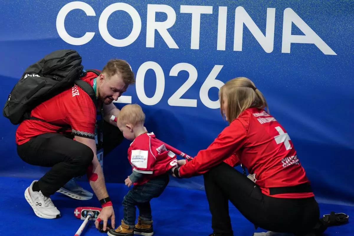 Switzerland's Yannick Schwaller and Briar Schwaller-Huerlimann interact with their child after the mixed doubles round robin phase of the curling competition against Canada, at the 2026 Winter Olympics, in Cortina d'Ampezzo, Italy, Sunday, Feb. 8, 2026. (AP Photo/Misper Apawu)
