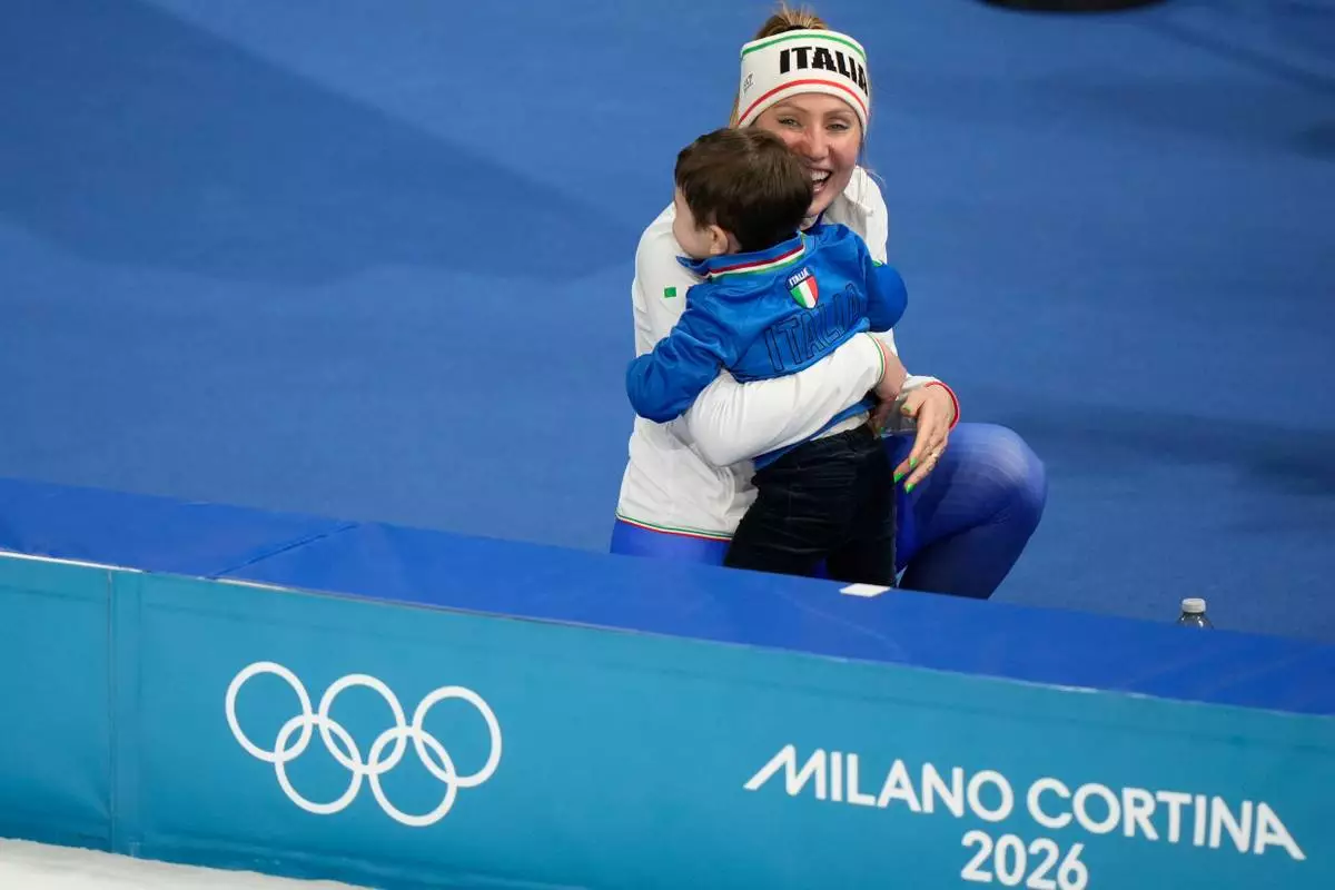 Francesca Lollobrigida of Italy celebrates with her son Tommaso after winning the gold medal in the women's 3,000 meters speedskating race at the 2026 Winter Olympics, in Milan, Italy, Saturday, Feb. 7, 2026. (AP Photo/Luca Bruno)