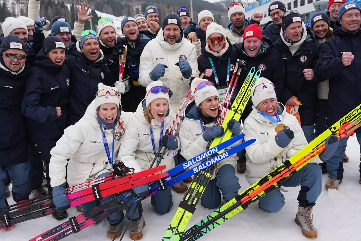 Haakon, Crown Prince of Norway, center, poses with Heidi Weng, Karoline Simpson-Larsen, Astrid Oeyre Slind, and Kristin Austgulen Fosnaes, of Norway, and their team after they won the gold medal in the cross country skiing women's 4 x 7.5km relay at the 2026 Winter Olympics, in Tesero, Italy, Saturday, Feb. 14, 2026. (AP Photo/Matthias Schrader)