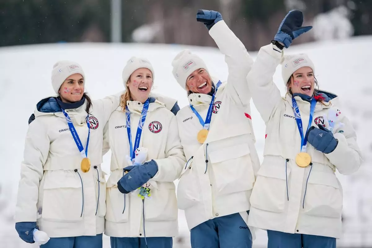 Heidi Weng, Karoline Simpson-Larsen, Astrid Oeyre Slind, and Kristin Austgulen Fosnaes, of Norway, celebrate on the podium after winning the gold medal in the cross country skiing women's 4 x 7.5km relay at the 2026 Winter Olympics, in Tesero, Italy, Saturday, Feb. 14, 2026. (AP Photo/Matthias Schrader)