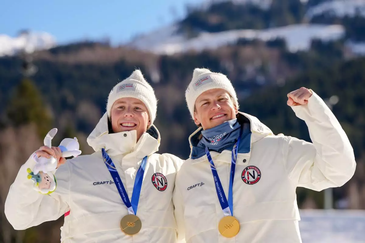 Johannes Hoesflot Klaebo and Einar Hedegart, of Norway, pose after winning the gold medal in cross-country skiing men's team sprint free at the 2026 Winter Olympics, in Tesero, Italy, Wednesday, Feb. 18, 2026. (AP Photo/Kirsty Wigglesworth)