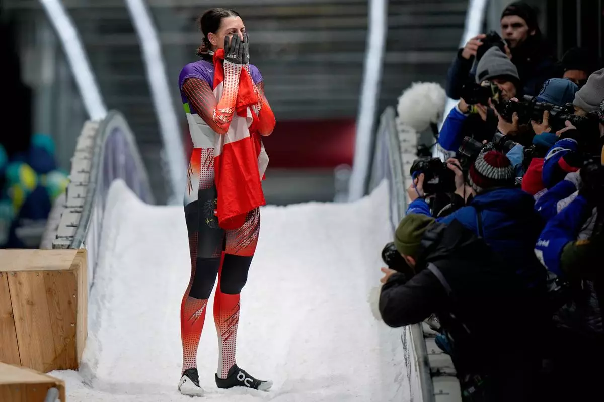 Austria's gold medalist Janine Flock celebrates as she arrives at the finish during a women's skeleton run at the 2026 Winter Olympics, in Cortina d'Ampezzo, Italy, Saturday, Feb. 14, 2026. (AP Photo/Aijaz Rahi)