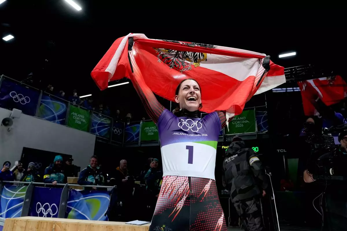 Austria's gold medalist Janine Flock celebrates as she arrives at the finish during a women's skeleton run at the 2026 Winter Olympics, in Cortina d'Ampezzo, Italy, Saturday, Feb. 14, 2026. (AP Photo/Alessandra Tarantino)