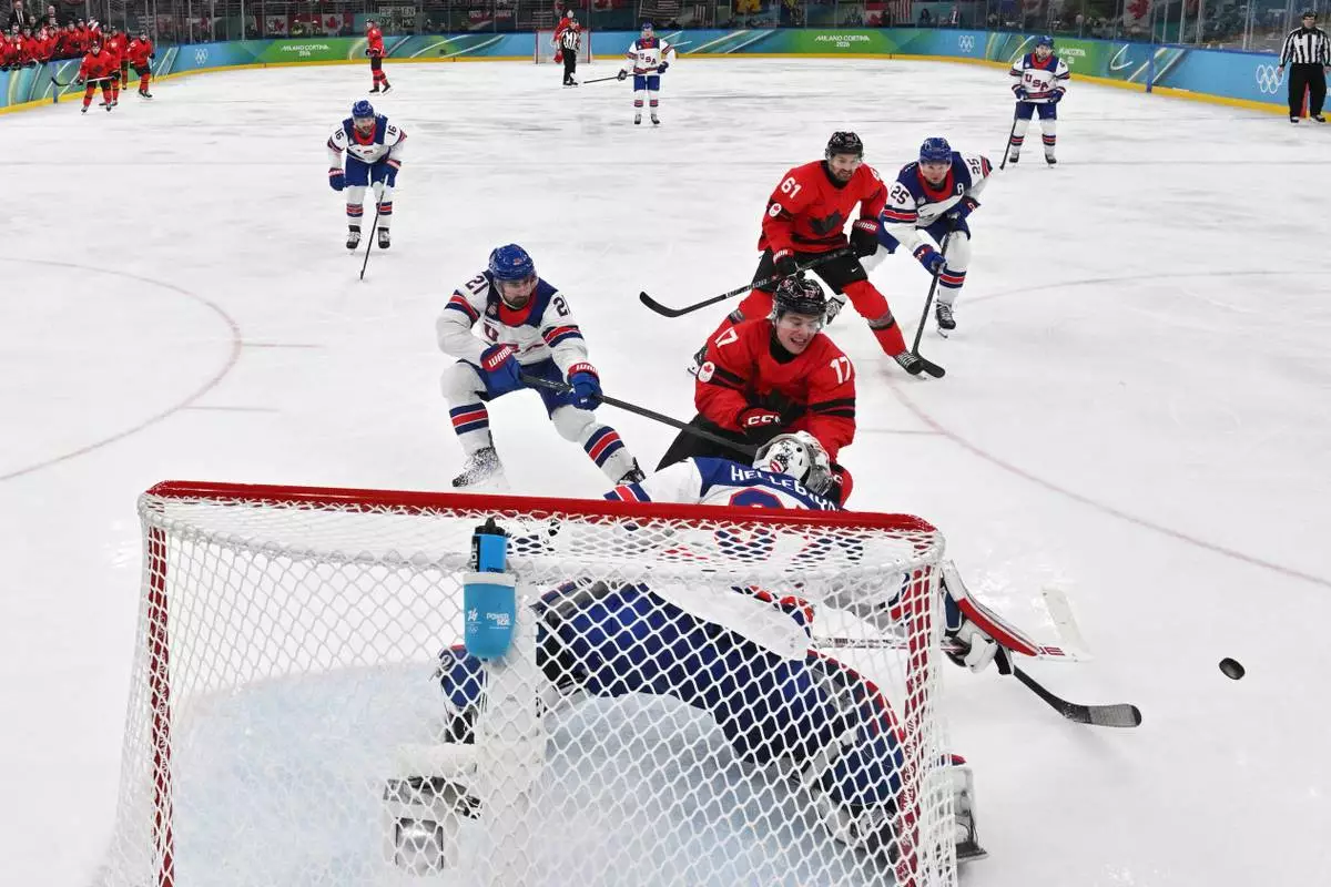 Canada's Macklin Celebrini and United States' Connor Hellebuyck vie for the puck, during the men's ice hockey gold medal game, at the 2026 Winter Olympics in Milan, Italy, Sunday, Feb. 22, 2026. (Julien De Rosa/Pool Photo via AP)