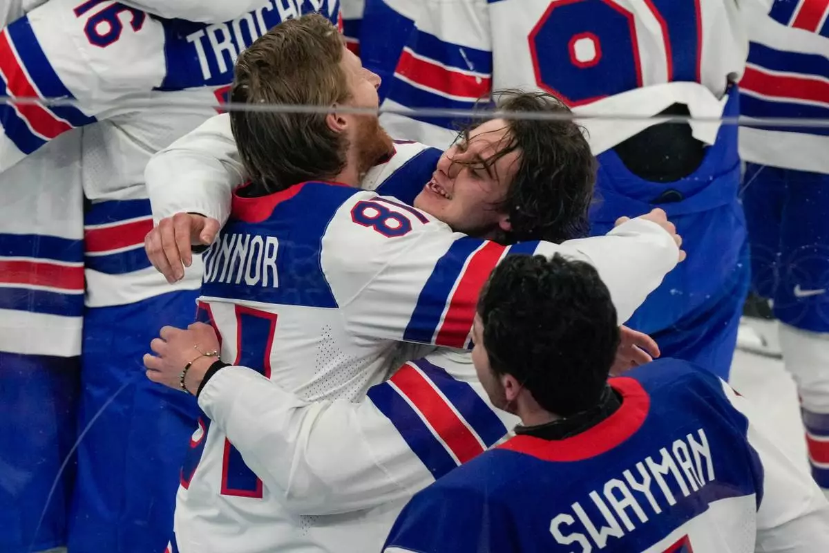 United States' Jack Hughes (86) celebrates with goalie Connor Hellebuyck (37) after scoring the game-winning goal against Canada in sudden death overtime during the men's ice hockey gold medal game at the 2026 Winter Olympics, in Milan, Italy, Sunday, Feb. 22, 2026. (AP Photo/Luca Bruno)