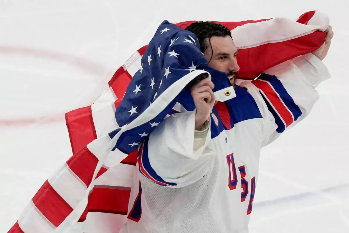 United States' Connor Hellebuyck (37) skates around the ice with the American flag after the US defeated Canada in the men's ice hockey gold medal game at the 2026 Winter Olympics, in Milan, Italy, Sunday, Feb. 22, 2026. (AP Photo/Luca Bruno)