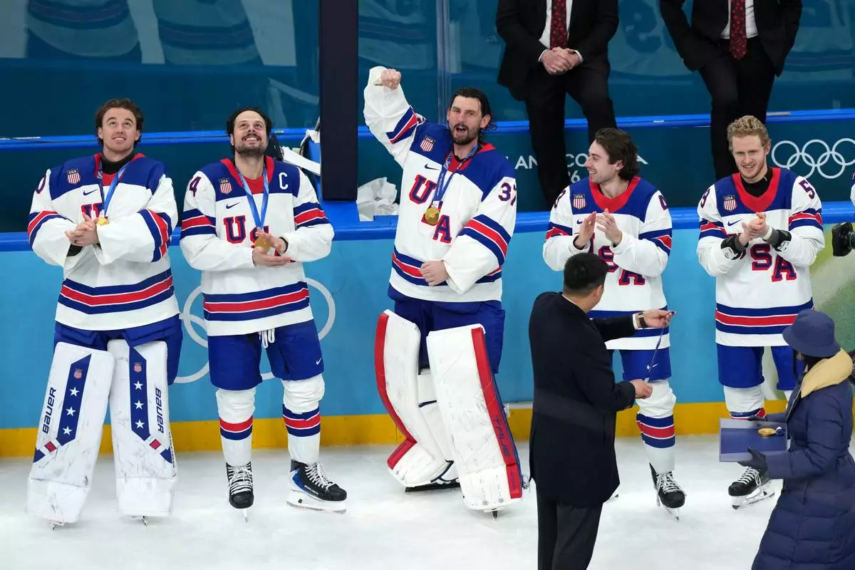 United States goalkeeper Connor Hellebuyck (37) celebrates as player receive their medals after defeating Canada in overtime to win the men's ice hockey gold medal game at the 2026 Winter Olympics in Milan, Italy, Sunday, Feb. 22, 2026. (AP Photo/Carolyn Kaster)