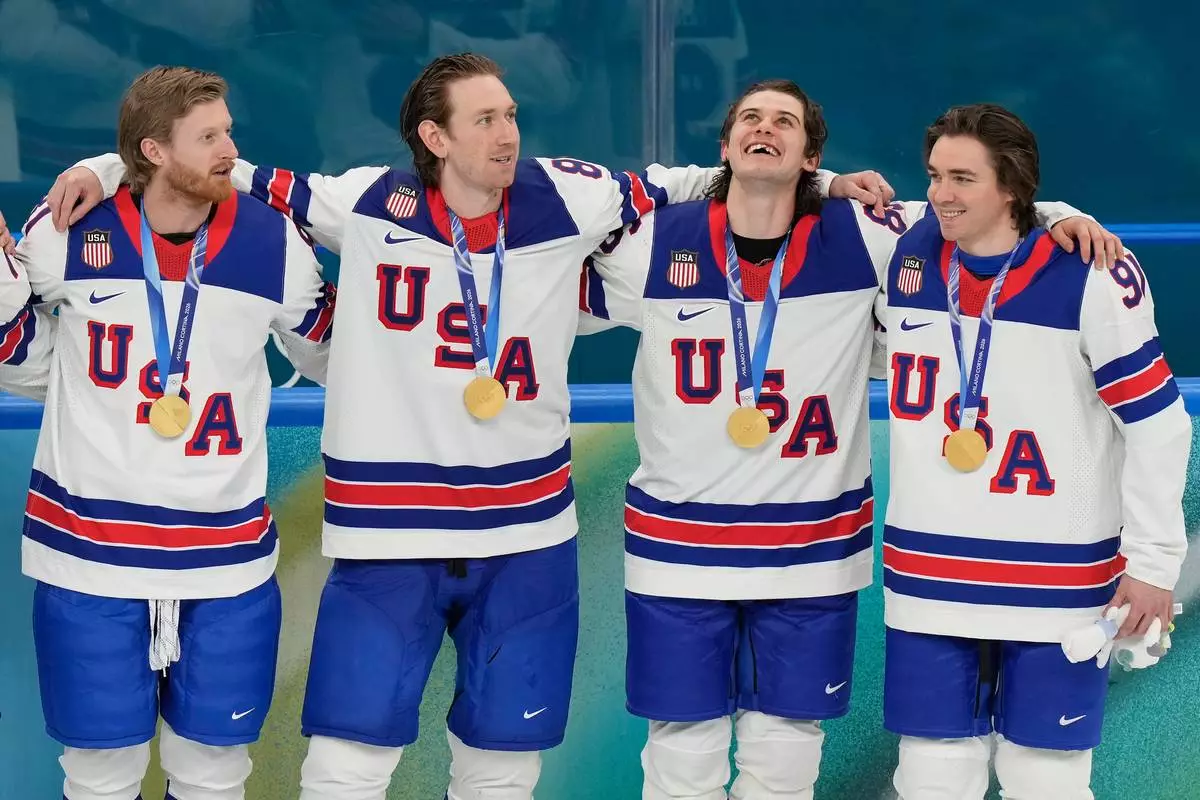 United States' Kyle Connor (81), Zach Werenski (8), Jack Hughes (86) and Clayton Keller (91) react after receiving their gold medals after the United States defeated Canada in the men's ice hockey gold medal game at the 2026 Winter Olympics, in Milan, Italy, Sunday, Feb. 22, 2026. (AP Photo/Luca Bruno)