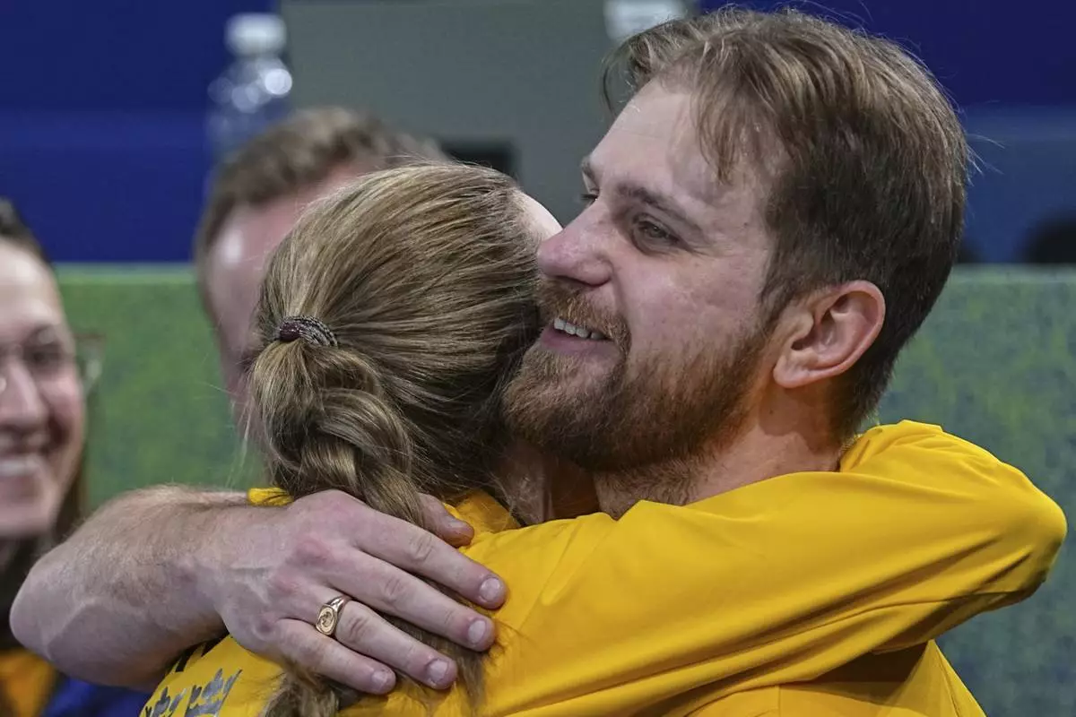 Sweden's Rasmus Wranaa and Isabella Wranaa hug during the mixed doubles round robin phase of the curling competition against Canada, at the 2026 Winter Olympics, in Cortina d'Ampezzo, Italy, Sunday, Feb. 8, 2026. (AP Photo/Fatima Shbair)
