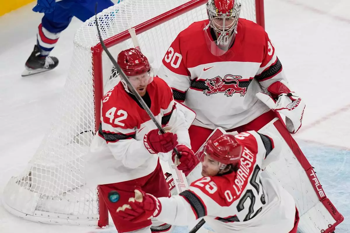 Denmark's Oliver Lauridsen reaches for the puck during a preliminary round match of men's ice hockey between United States and Denmark at the 2026 Winter Olympics, in Milan, Italy, Saturday, Feb. 14, 2026. (AP Photo/Petr David Josek)