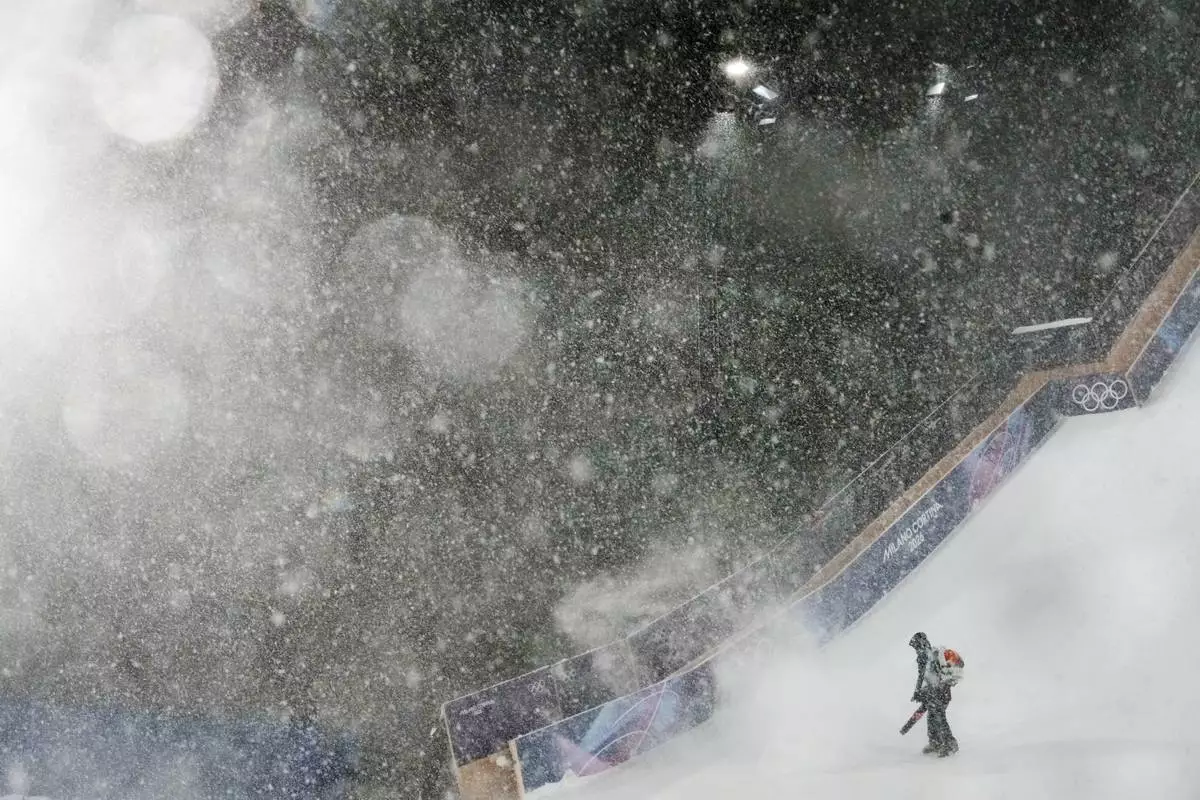 A worker blows snow off the course during heavy snow before the women's freestyle skiing big air finals at the 2026 Winter Olympics, in Livigno, Italy, Monday, Feb. 16, 2026. (AP Photo/Abbie Parr)