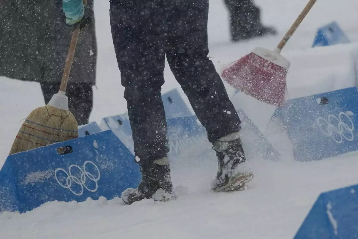Workers remove snow on the finish area before the Biathlon Men's 4 x 7.5km Relay at the 2026 Winter Olympics, in Anterselva, Italy, Tuesday, Feb. 17, 2026. (AP Photo/Christophe Ena)