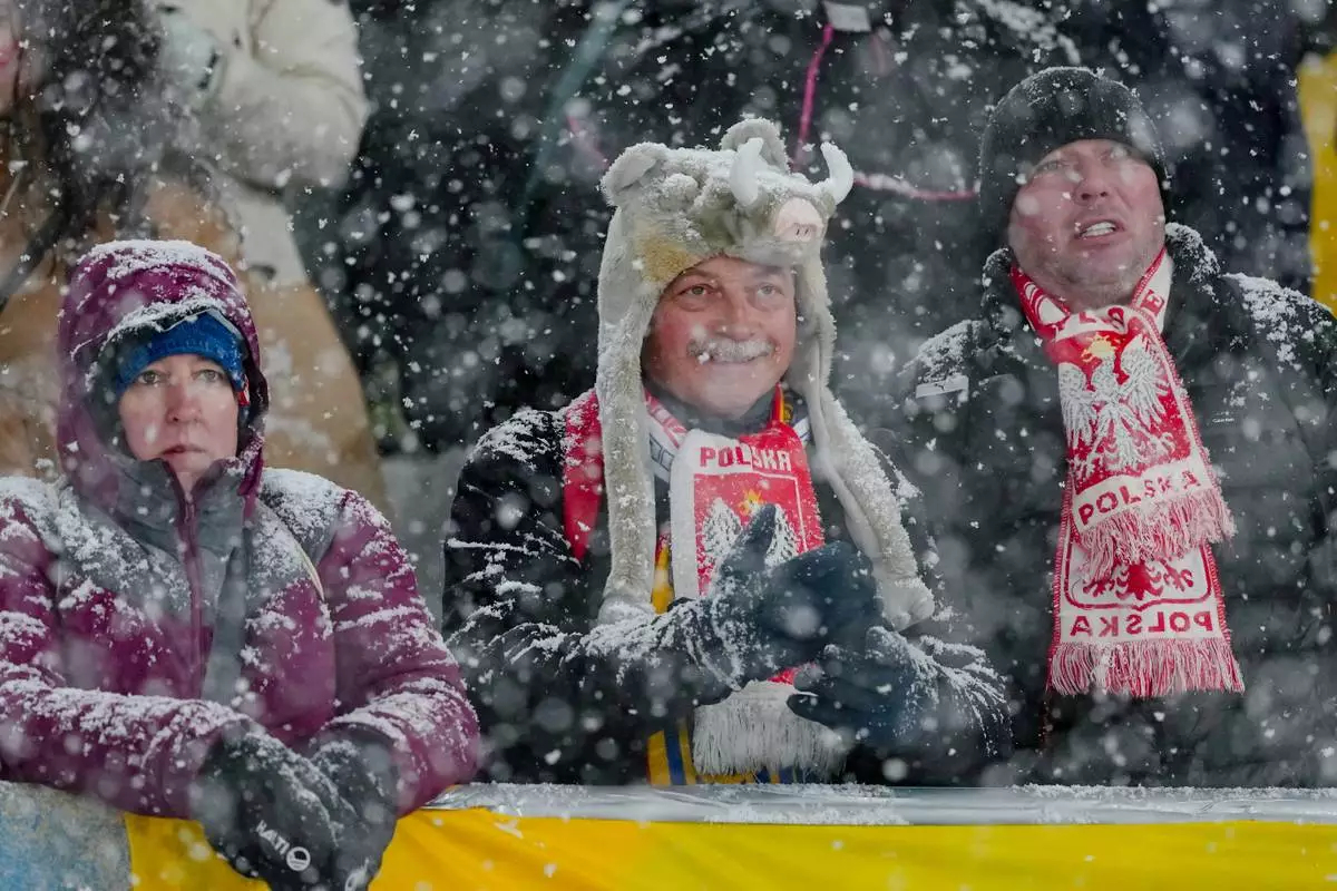 Poland fans wait while a snowfall interrupts the final round jump of the ski jumping men's super team competition at the 2026 Winter Olympics, in Predazzo, Italy, Monday, Feb. 16, 2026. (AP Photo/Matthias Schrader)