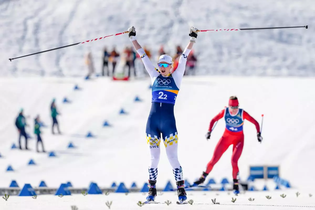 Maja Dahlqvist, of Sweden, crosses the finish line to win the gold medal, ahead of Nadine Faehndrich, of Switzerland, in the cross-country skiing women's team sprint free at the 2026 Winter Olympics, in Tesero, Italy, Wednesday, Feb. 18, 2026. (AP Photo/Kirsty Wigglesworth)