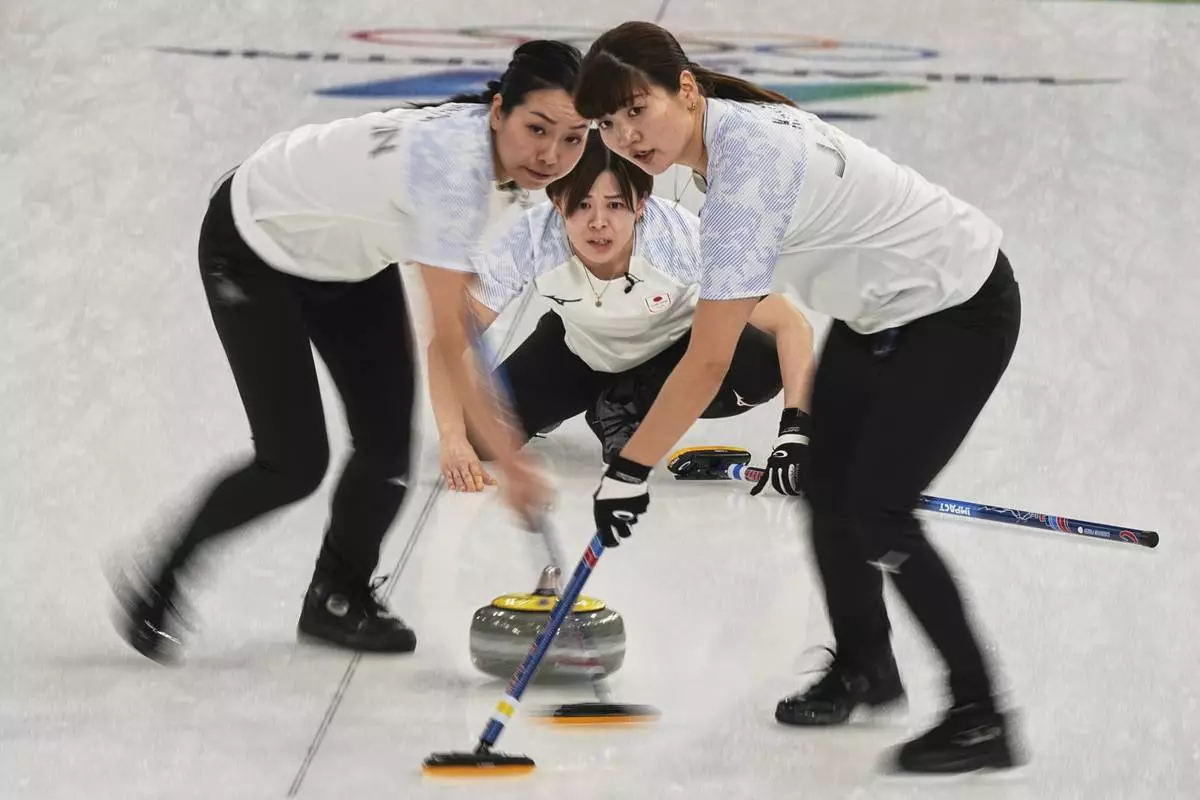 Japan's Yuna Kotani, Anna Ohmiya and Kaho Onodera in action during the women's curling round robin session against Britain at the 2026 Winter Olympics, in Cortina d'Ampezzo, Italy, Wednesday, Feb. 18, 2026. (AP Photo/Fatima Shbair)
