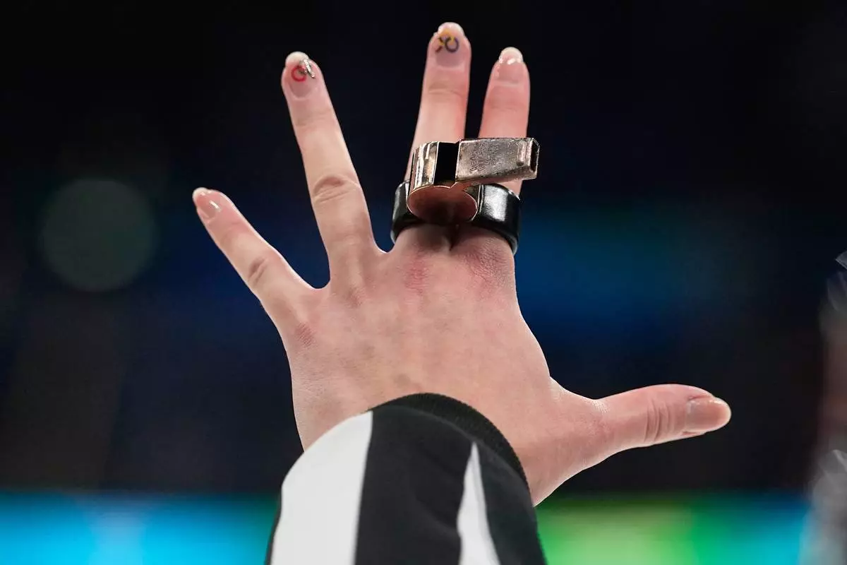 A referee signals with her hand during a women's ice hockey bronze medal game between Switzerland and Sweden at the 2026 Winter Olympics, in Milan, Italy, Thursday, Feb. 19, 2026. (AP Photo/Hassan Ammar)
