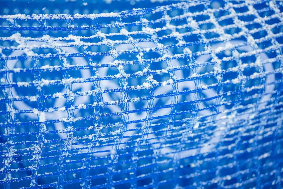 Snow gathers on a net fence at the ski jumping venue ahead of the nordic combined team sprint at the 2026 Winter Olympics, in Predazzo, Italy, Thursday, Feb. 19, 2026. (AP Photo/Matthias Schrader)