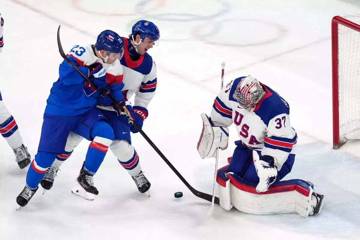 Slovakia's Adam Liska (23) battles with United States' Brock Faber, center, for the puck in front of United States goalkeeper Connor Hellebuyck (37) during the third period of a men's ice hockey semifinal game at the 2026 Winter Olympics in Milan, Italy, Friday, Feb. 20, 2026. (AP Photo/Carolyn Kaster)