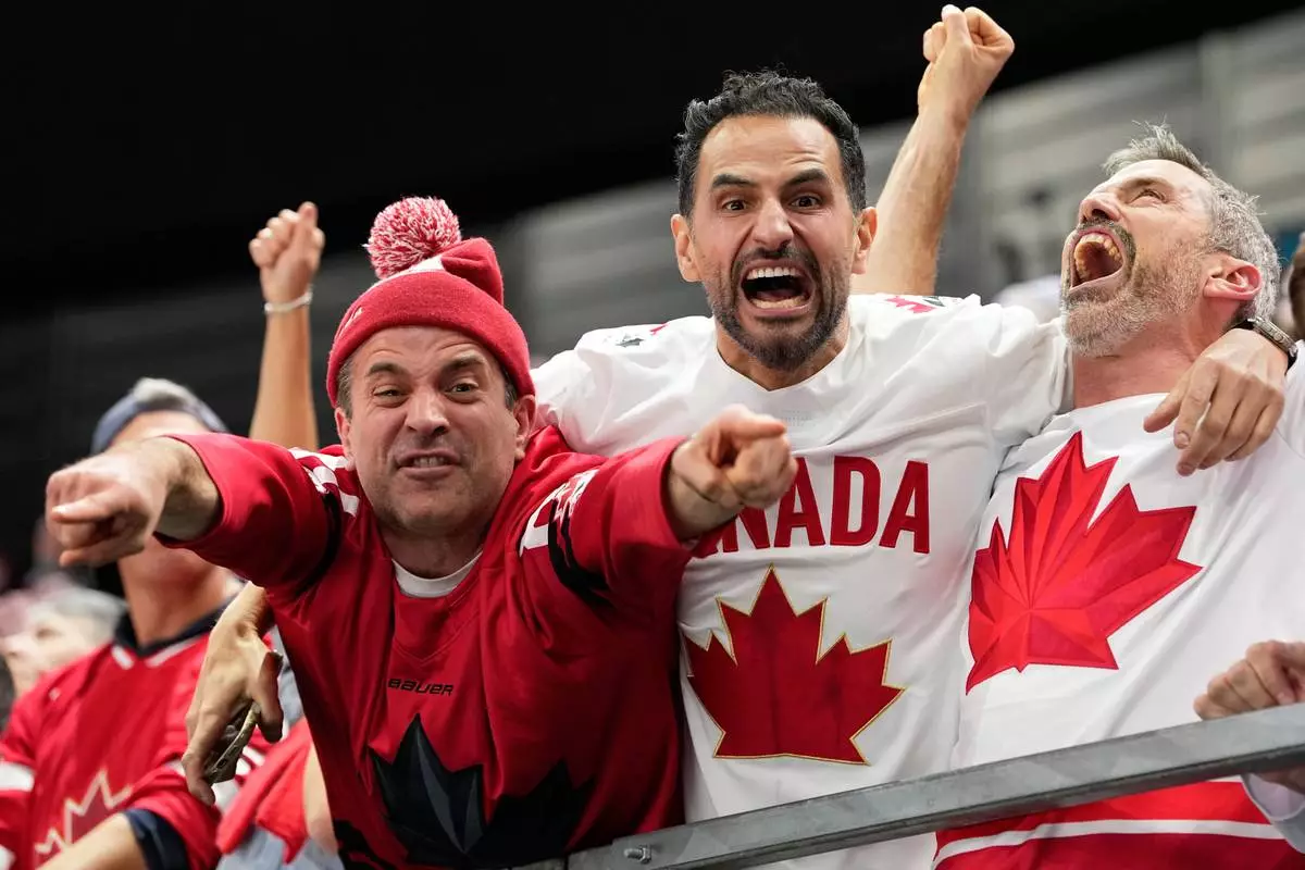 Canada supporters celebrate after Canada's Shea Theodore (27) scored his side's second goal during a men's ice hockey semifinal game between Canada and Finland at the 2026 Winter Olympics, in Milan, Italy, Friday, Feb. 20, 2026. (AP Photo/Hassan Ammar)