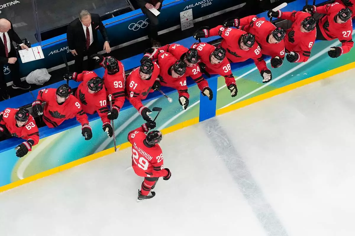 Canada's Nathan MacKinnon (29) celebrates with teammates after scoring the game-winning goal against Finland during a men's semifinal ice hockey game at the 2026 Winter Olympics, in Milan, Italy, Friday, Feb. 20, 2026. (AP Photo/David J. Phillip)