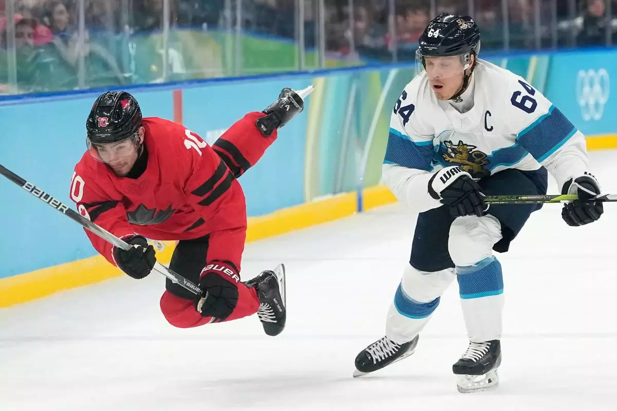 Canada's Nick Suzuki (10) challenges with Finland's Mikael Granlund (64) during a men's ice hockey semifinal game between Canada and Finland at the 2026 Winter Olympics, in Milan, Italy, Friday, Feb. 20, 2026. (AP Photo/Hassan Ammar)