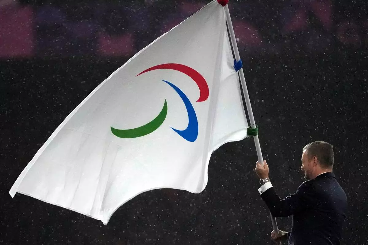 FILE - President of the International Paralympic Committee Andrew Parsons passes the Paralympic flag to Mayor of Los Angeles Karen Bass, not pictured, after receiving it from Mayor of Paris Anne Hidalgo, not pictured, during the closing ceremony of the 2024 Paralympics, Sept. 8, 2024, in Paris. (AP Photo/Michel Euler, File)