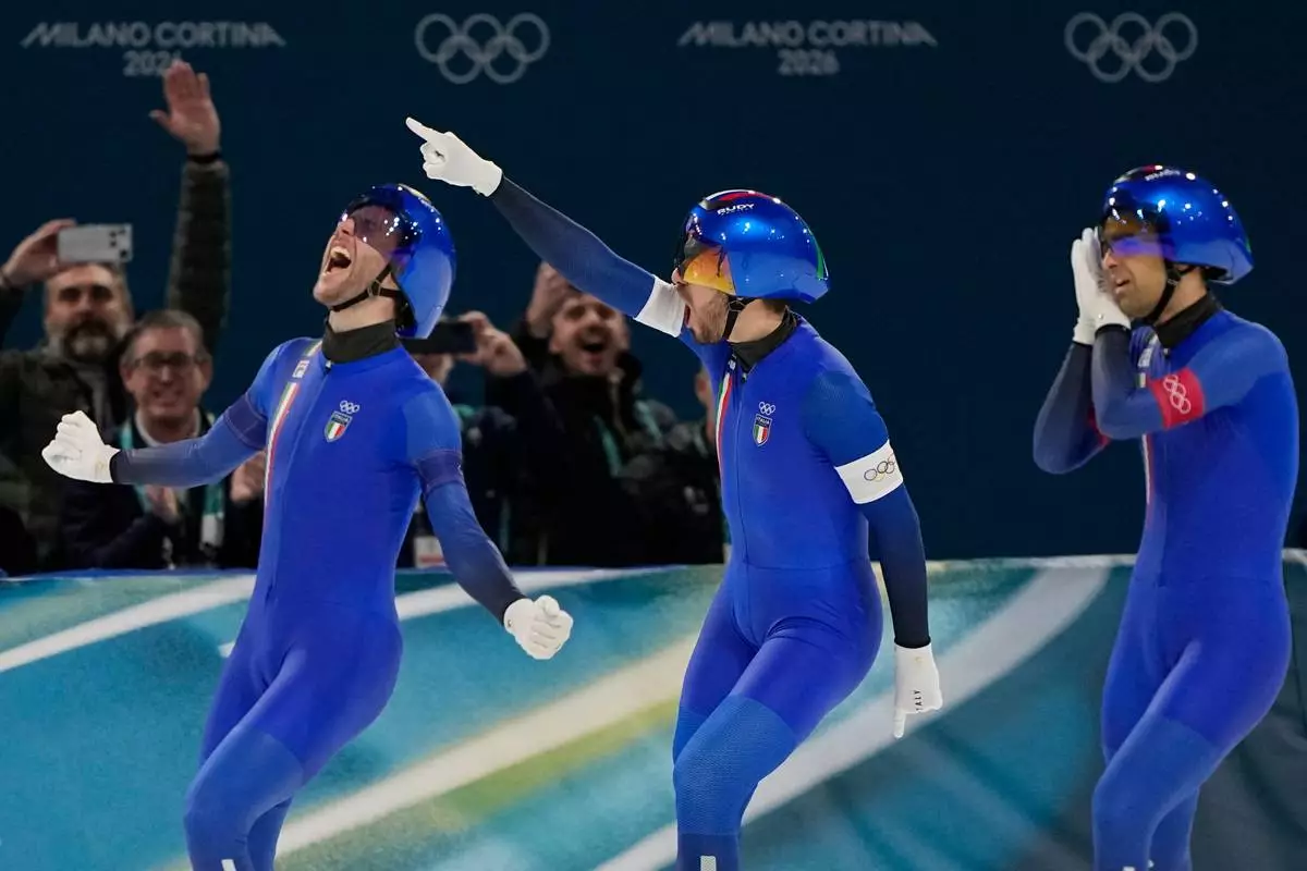 Team Italy with Michele Malfatti, left, Davide Ghiotto, center, and Andrea Giovannini, right, celebrate winning the gold medal in the final of the men's team pursuit speedskating race at the 2026 Winter Olympics, in Milan, Italy, Tuesday, Feb. 17, 2026. (AP Photo/Ben Curtis)
