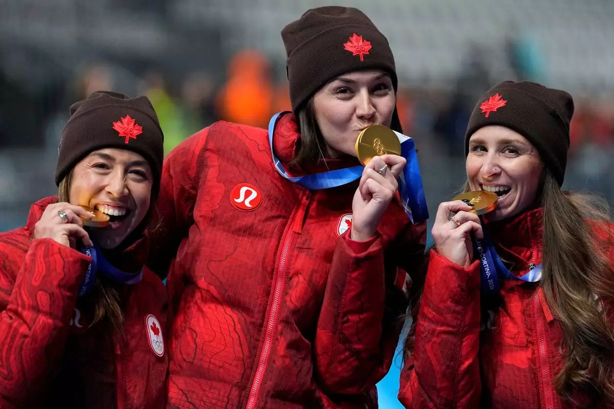 Team Canada with Isabelle Weidemann, center, Valerie Maltais, left, and Ivanie BLondin, right, celebrate winning the gold medal in the final of the women's team pursuit speedskating race at the 2026 Winter Olympics, in Milan, Italy, Tuesday, Feb. 17, 2026. (AP Photo/Ben Curtis)