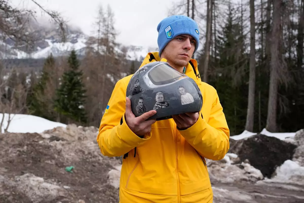 Ukrainian skeleton athlete Vladyslav Heraskevych holds his crash helmet as he stands outside the sliding center at the 2026 Winter Olympics, in Cortina d'Ampezzo, Italy, Thursday, Feb. 12, 2026. (AP Photo/Alessandra Tarantino)